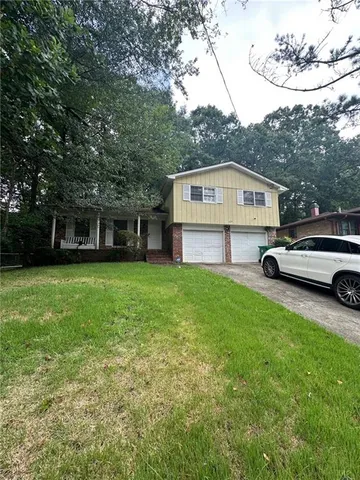 a front view of a house with a garden and trees