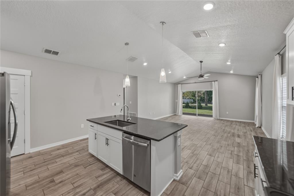 13907 9th Street Dade City, FL 33525 - Photo 15 of 43 a kitchen with stainless steel appliances granite countertop a sink stove and wooden floor