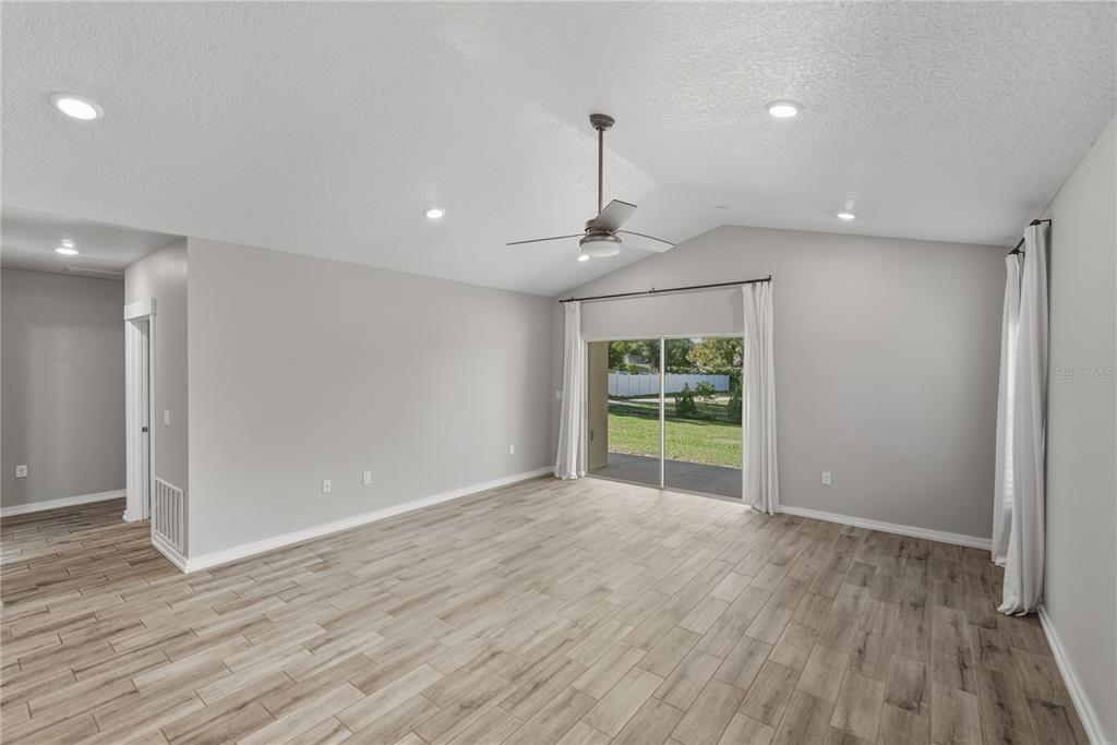13907 9th Street Dade City, FL 33525 - Photo 17 of 43 a view of an empty room with wooden floor fridge and a window