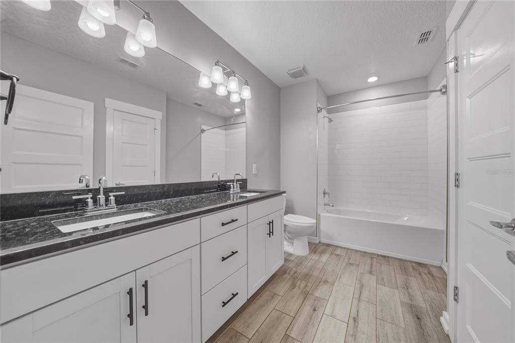 13907 9th Street Dade City, FL 33525 - Photo 30 of 43 a bathroom with a double vanity sink a toilet and a large mirror