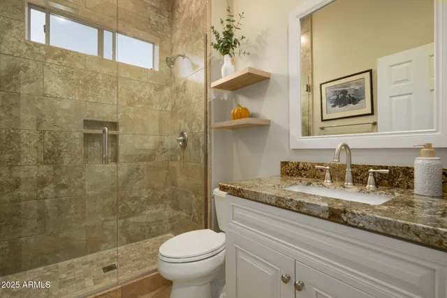a bathroom with a granite countertop sink a toilet and shower