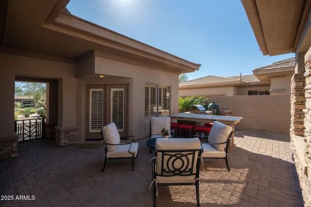 a patio with table and chairs and potted plants