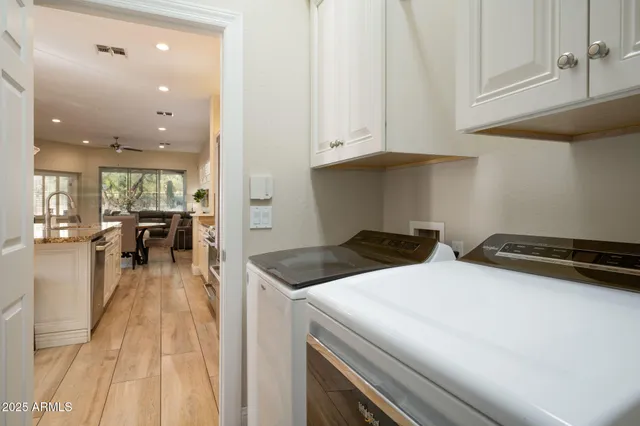 a kitchen that has a lot of white cabinets and stainless steel appliances