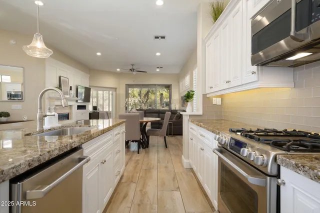 a kitchen with granite countertop a sink a counter top space stainless steel appliances and cabinets