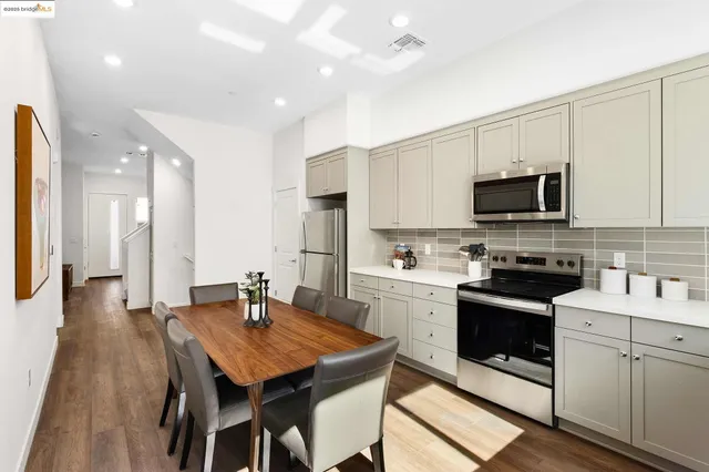 a kitchen with stainless steel appliances granite countertop a stove a sink a microwave a refrigerator and white cabinets with wooden floor