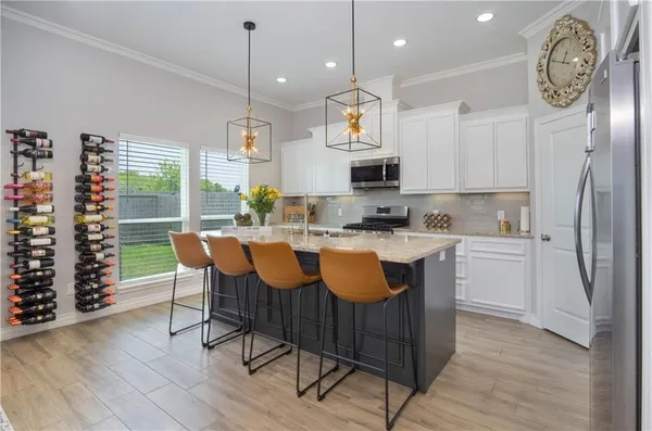 a kitchen with stainless steel appliances granite countertop a stove a refrigerator a kitchen island a sink dishwasher and white cabinets with wooden floor
