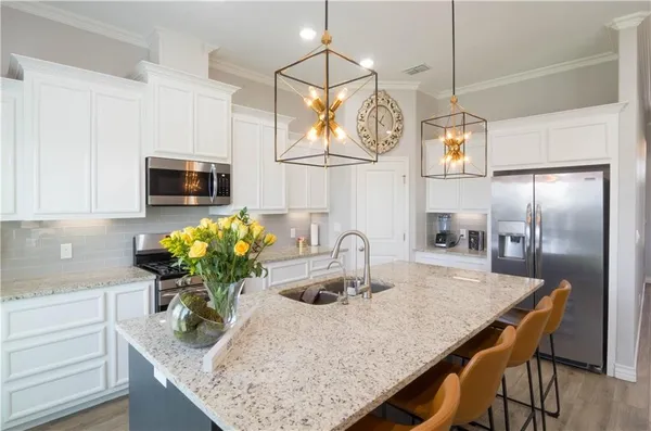 a kitchen with stainless steel appliances granite countertop a sink a kitchen island a stove a dining table and chairs with wooden floor