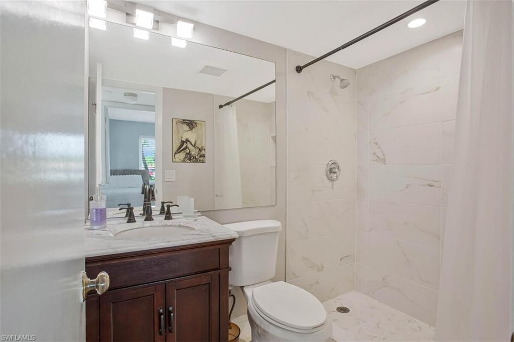 4380 27th Court Southwest, Unit 1 Naples, FL 34116 - Photo 14 of 34 Ensuite bathroom featuring vanity and walk in tiled shower
