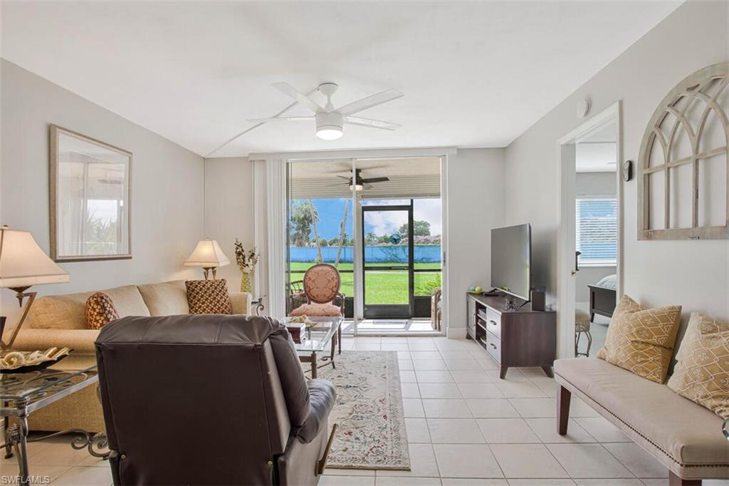4380 27th Court Southwest, Unit 1 Naples, FL 34116 - Photo 15 of 34 Light and bright Living room featuring a large TV, sofa and recliner, slider door to screened lanai