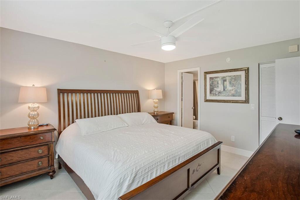4380 27th Court Southwest, Unit 1 Naples, FL 34116 - Photo 19 of 34 Bedroom featuring a ceiling fan, light tile patterned floors, and ensuite bathroom