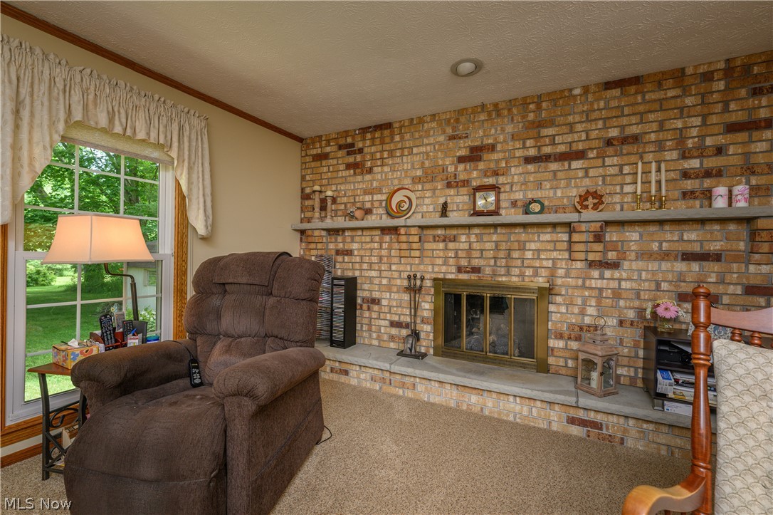 3281 Brenner Road Barberton, OH 44203 - Photo 19 of 33 Carpeted living room with brick wall, a fireplace, and a textured ceiling