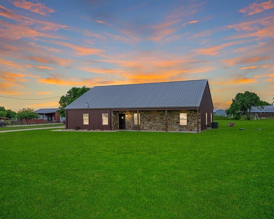 View of front of property with an outbuilding, cooling unit, and metal roof