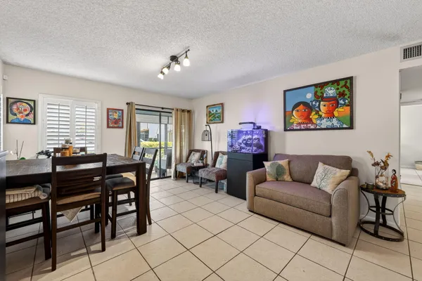 a living room with furniture a dining table and a flat screen tv with kitchen view