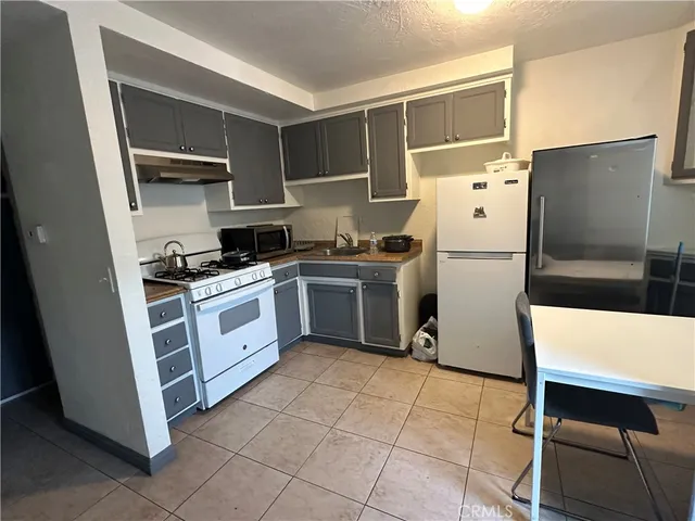a kitchen with white cabinets a refrigerator and a stove
