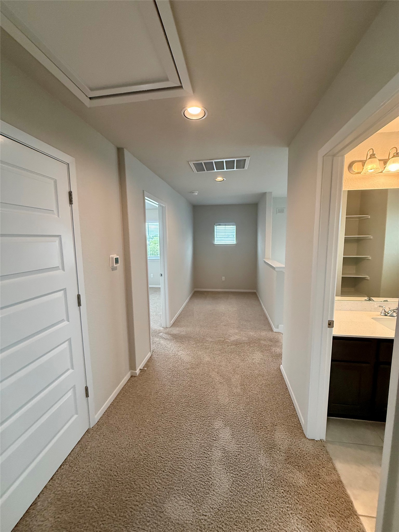212 Lake Placid Run Elgin, TX 78621 - Photo 10 of 27 A well-lit corridor featuring warm-toned carpet flooring and convenient ceiling access.