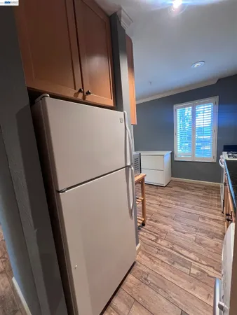 a room with wooden floor and a refrigerator