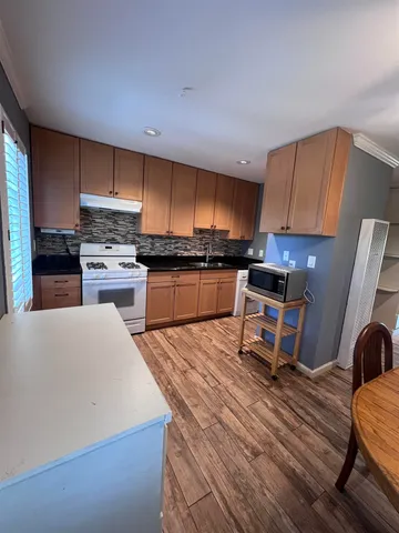 a kitchen with stainless steel appliances a stove a sink a refrigerator wooden floor and cabinets