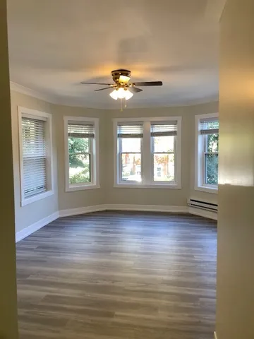 a view of an empty room with a window and wooden floor