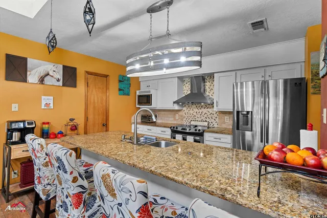 a kitchen with stainless steel appliances granite countertop a sink stove and refrigerator