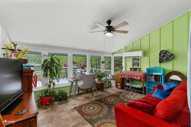 a living room with furniture a floor to ceiling window and a flat screen tv
