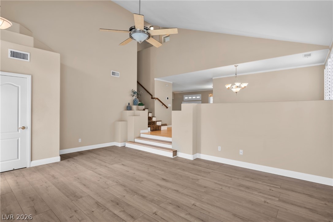 708 Vortex Avenue Henderson, NV 89002 - Photo 8 of 71 Natural wood-look flooring stretches across this open concept space with vaulted ceilings and a statement chandelier.