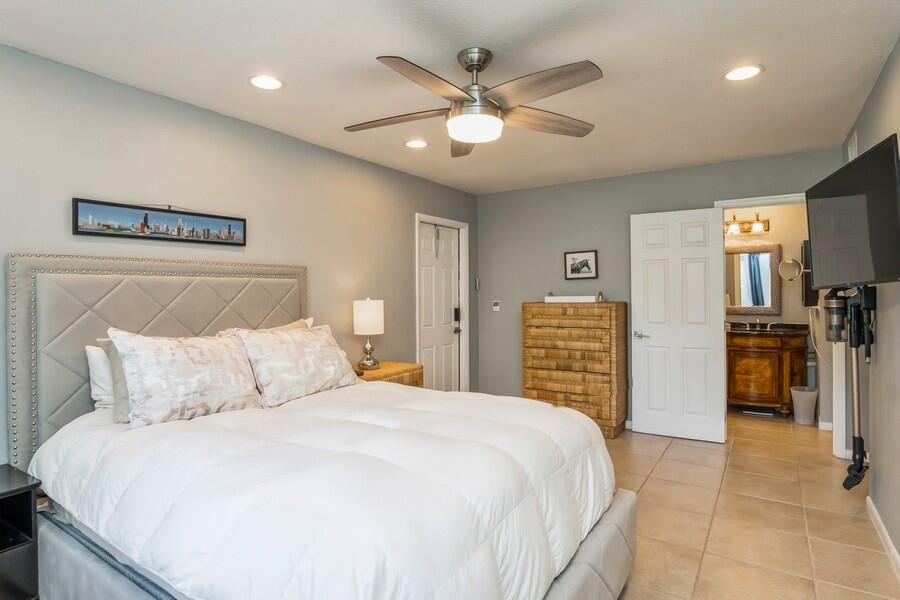 1230 South Drive Way, Unit A Delray Beach, FL 33445 - Photo 15 of 26 a bedroom with a large bed and a chandelier