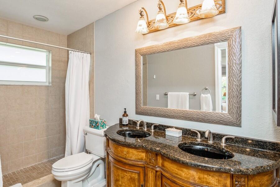 1230 South Drive Way, Unit A Delray Beach, FL 33445 - Photo 16 of 26 a bathroom with a granite countertop sink toilet a mirror and shower