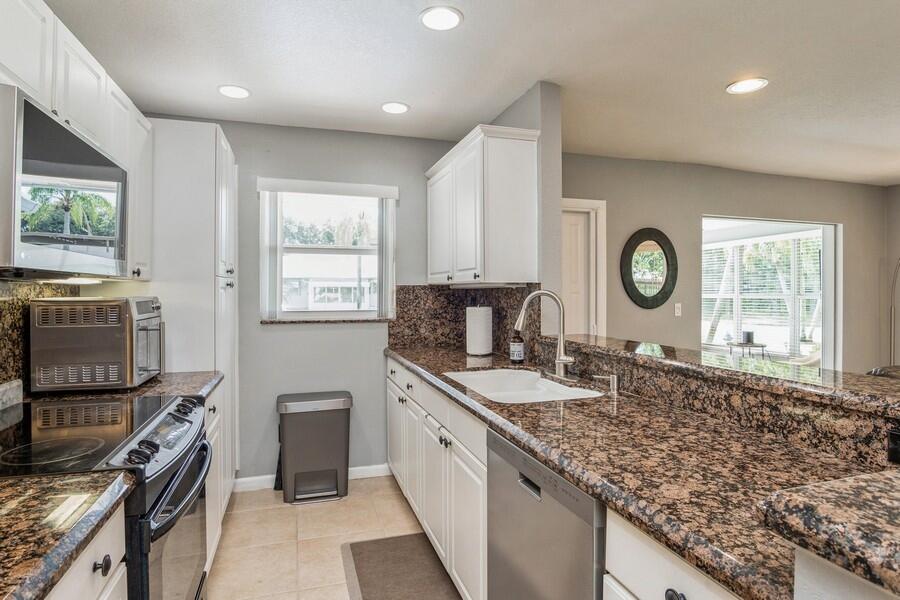 1230 South Drive Way, Unit A Delray Beach, FL 33445 - Photo 7 of 26 a kitchen with granite countertop a sink a stove top oven and cabinets