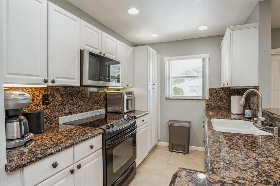 1230 South Drive Way, Unit A Delray Beach, FL 33445 - Photo 8 of 26 a kitchen with kitchen island granite countertop a stove sink and microwave