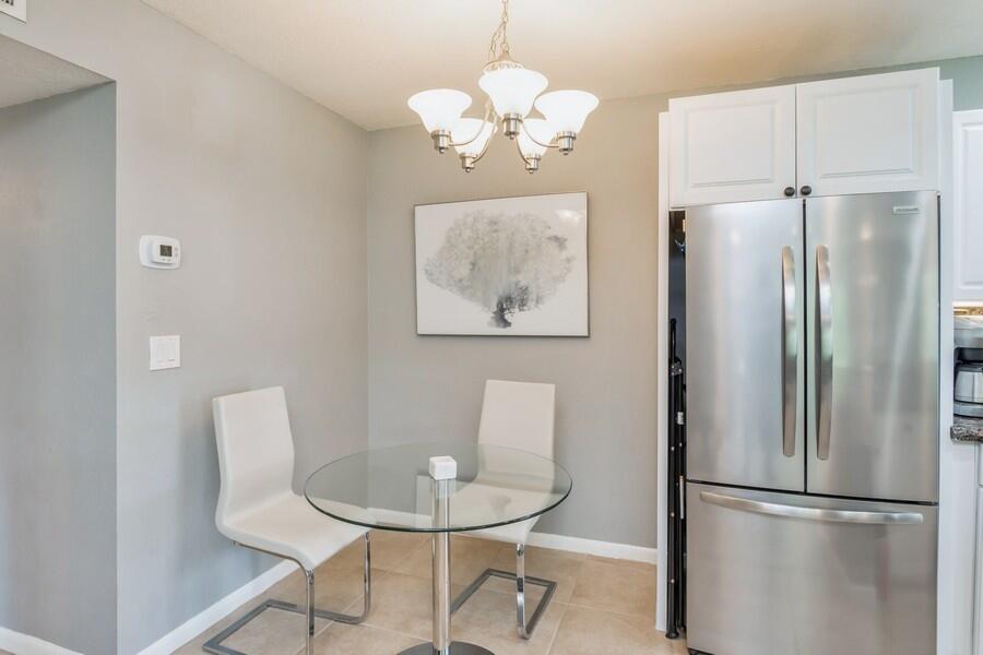 1230 South Drive Way, Unit A Delray Beach, FL 33445 - Photo 9 of 26 a dining room with wooden floor a glass table and chairs