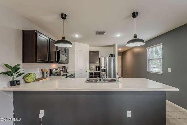 a kitchen with kitchen island a sink stainless steel appliances and a counter top space