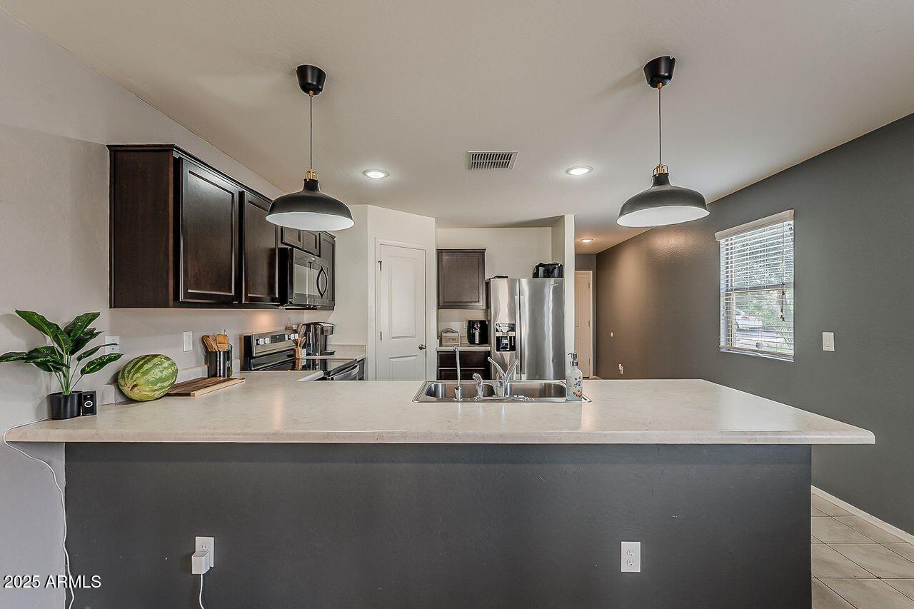8721 South 253rd Drive Buckeye, AZ 85326 - Photo 9 of 44 a kitchen with kitchen island a sink stainless steel appliances and a counter top space