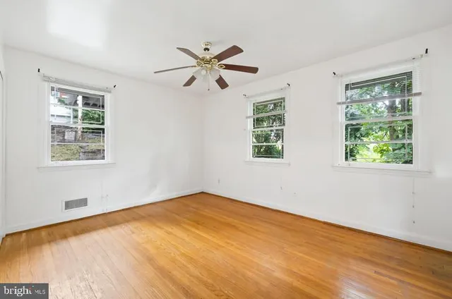 a view of empty room with wooden floor and fan