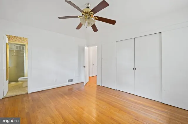 an empty room with wooden floor and a ceiling fan
