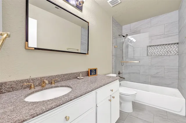 a bathroom with a granite countertop sink mirror toilet and bathtub