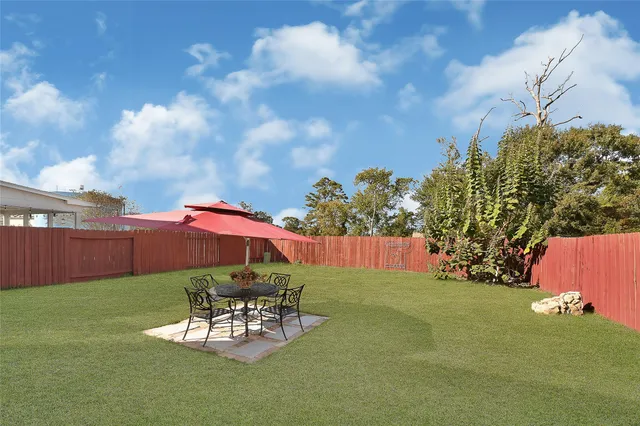 a view of a backyard with table and chairs potted plants and wooden fence