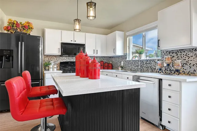 a kitchen with stainless steel appliances kitchen island granite countertop a table chairs in it and a wooden floors