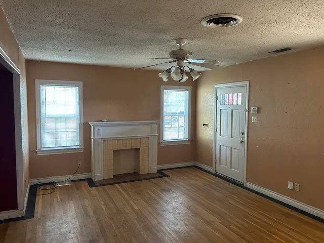 an empty room with wooden floor fan and windows