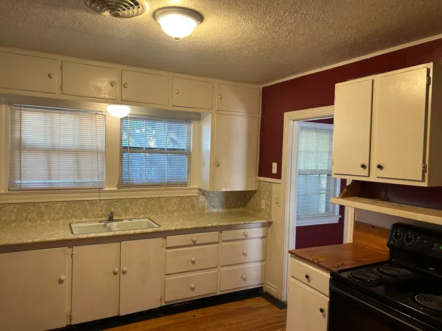 a kitchen with granite countertop white cabinets and window