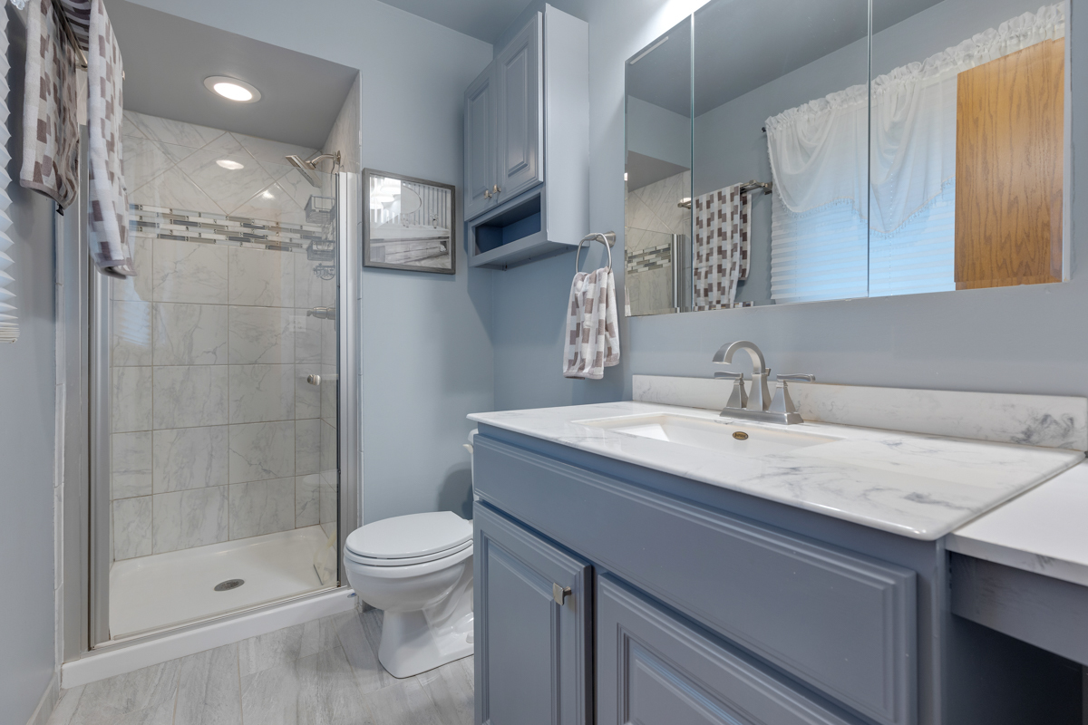 13031 Winnebago Road Palos Heights, IL 60463 - Photo 16 of 31 a bathroom with a granite countertop sink a toilet a mirror and shower