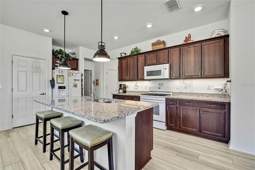 9764 Southwest 100th Avenue Ocala, FL 34481 - Photo 14 of 37 a kitchen with stainless steel appliances granite countertop a kitchen island a stove a sink a refrigerator and a cabinets
