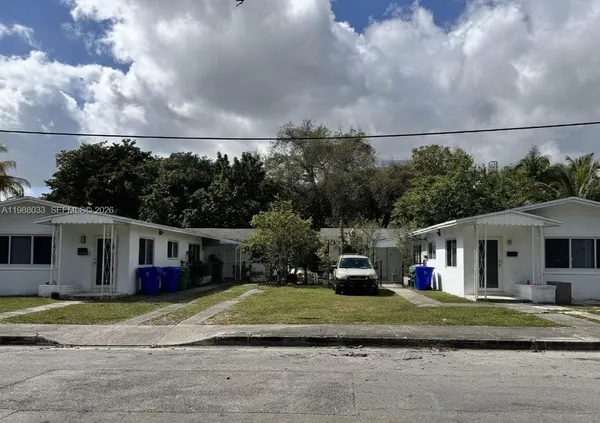 a view of a white house with a big yard and potted plants