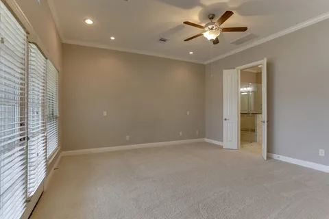 a view of an empty room and a ceiling fan and window
