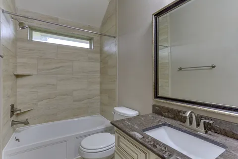 a bathroom with a granite countertop sink toilet a mirror and shower
