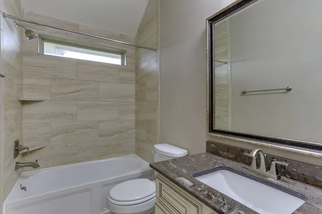 a bathroom with a granite countertop sink toilet a mirror and shower
