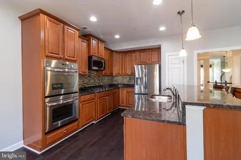 a kitchen with stainless steel appliances granite countertop a refrigerator a stove top oven a sink and dishwasher