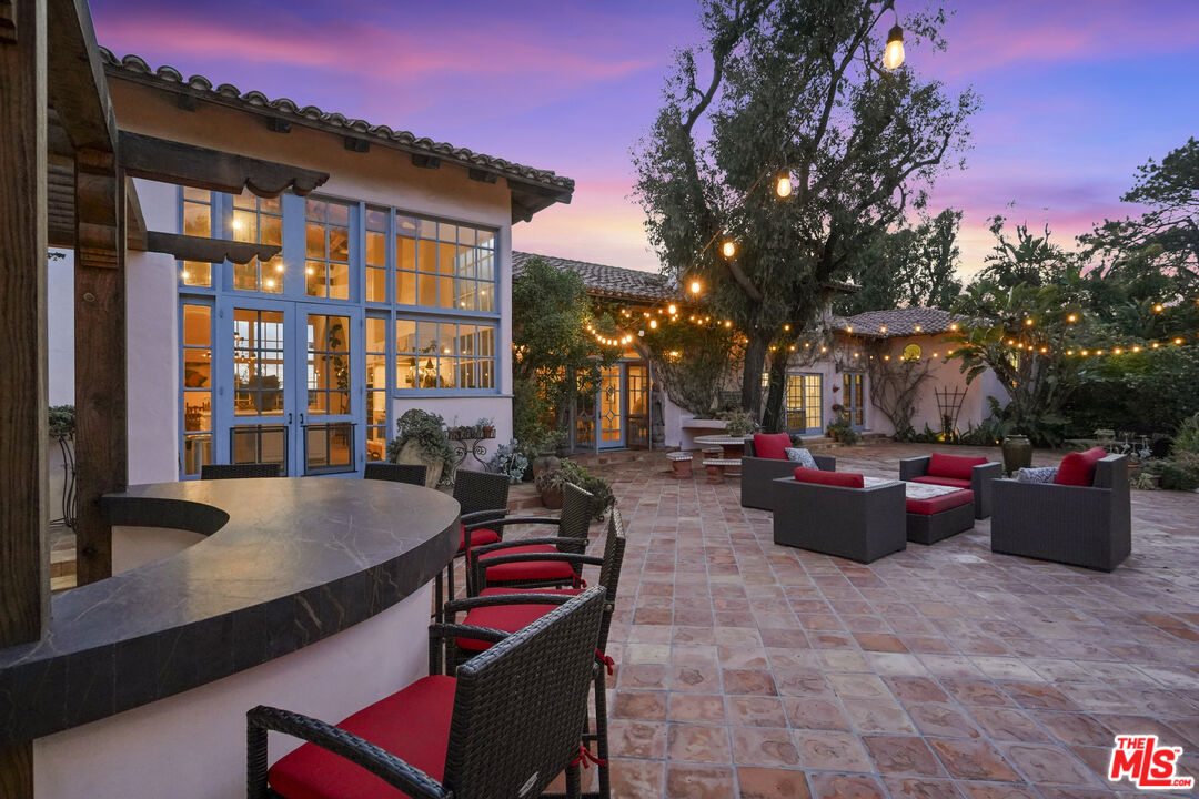7332 Birdview Avenue Malibu, CA 90265 - Photo 59 of 71 a view of a patio with couches and table and chairs with potted plants and big yard