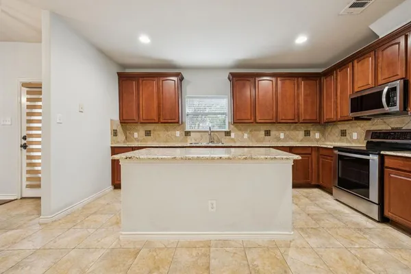 a kitchen with kitchen island granite countertop a stove sink and cabinets