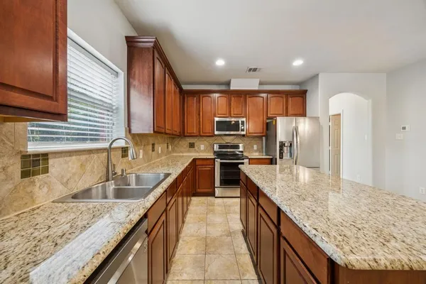 a kitchen with stainless steel appliances granite countertop a sink dishwasher stove refrigerator and cabinets