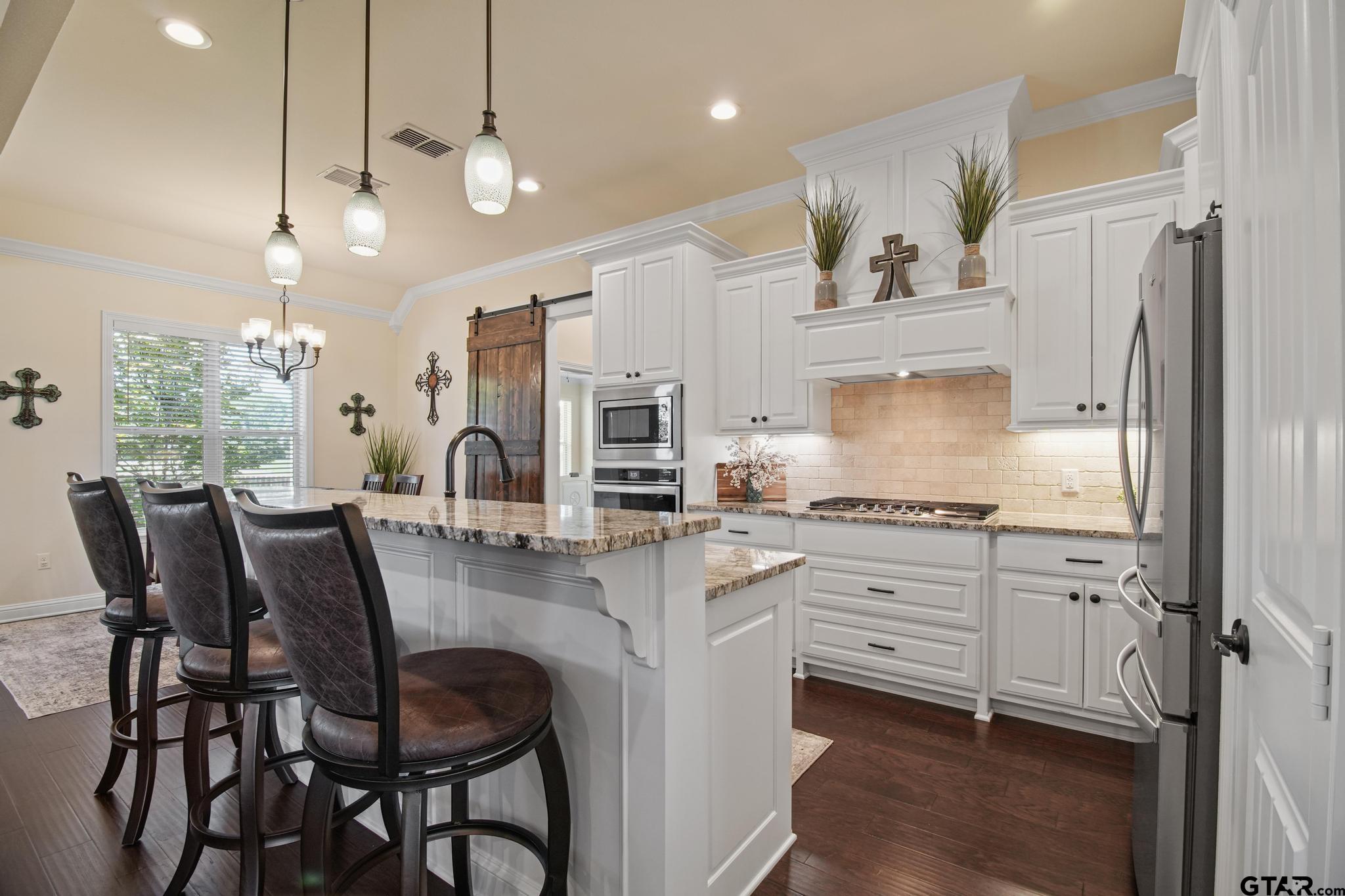 109 Nathan Road Chandler, TX 75758 - Photo 8 of 48 a kitchen with stainless steel appliances kitchen island granite countertop a stove a refrigerator and a dining table with wooden floor